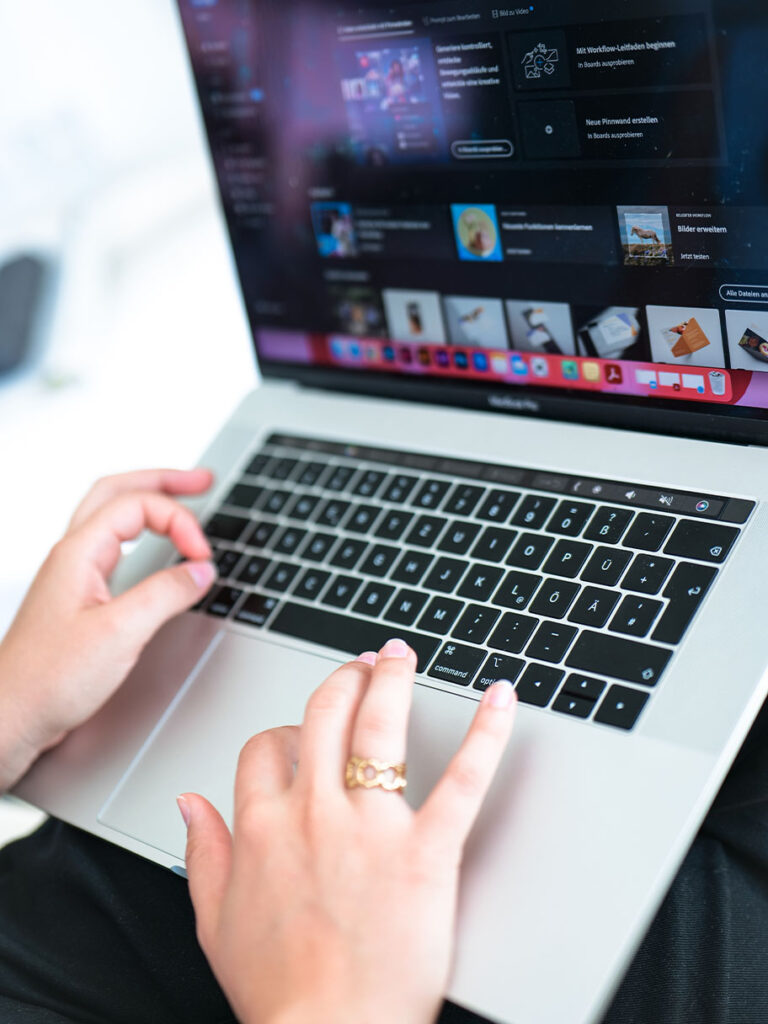 Hände bei der digitalen Designarbeit am Laptop mit geöffneter Adobe-Bildbearbeitungssoftware im Kommunikationsdesign-Portfolio von Alissia Ingra.